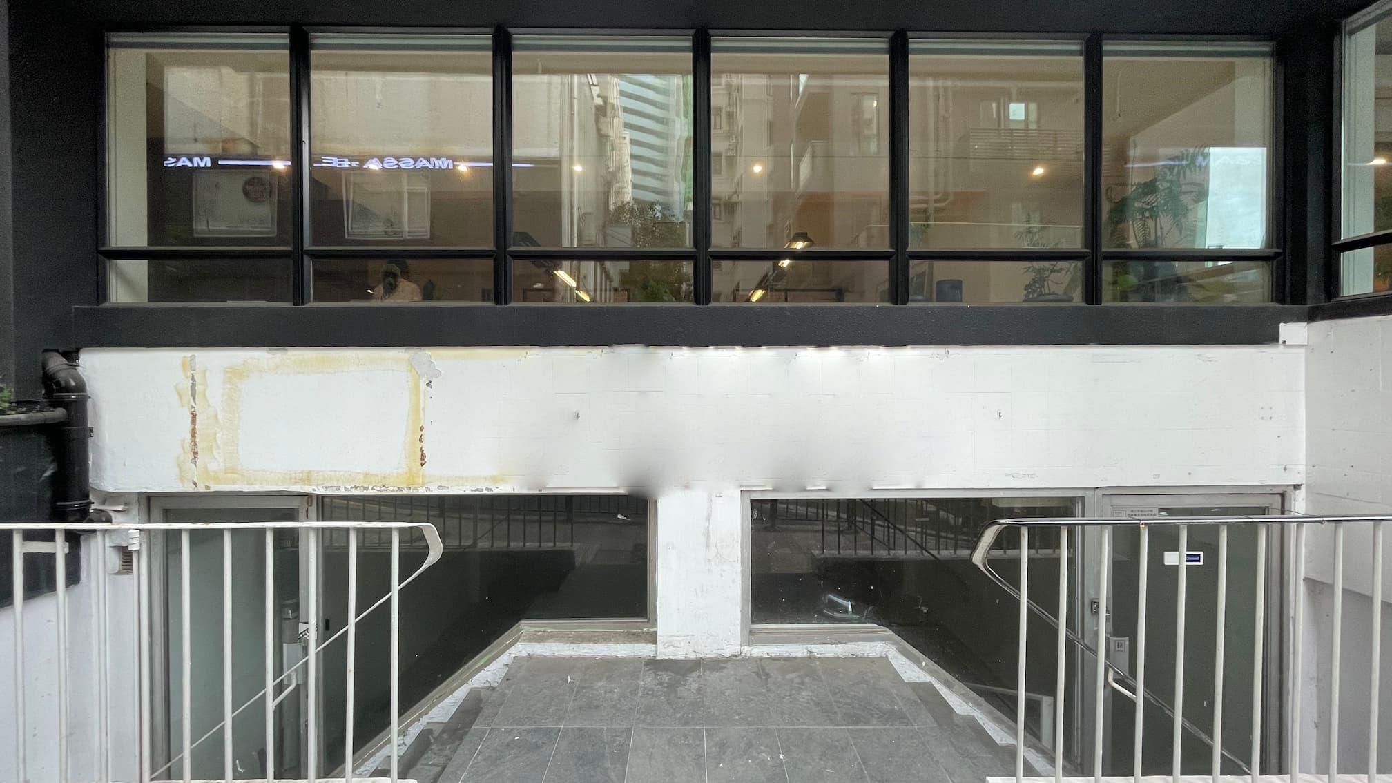 Ref#3644: Modern building with large upper glass windows, two glass door entrances below divided by a white wall—perfect for a shop, office, or restaurant. Features white railings and gray tiled steps for an inviting look.