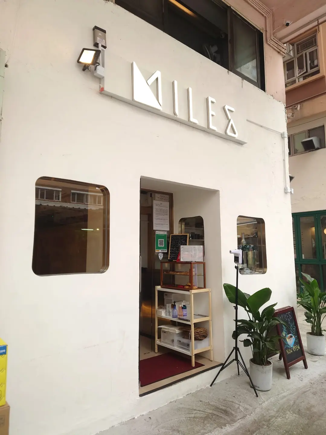 Ref#3647 features a cafe exterior with a white facade, two square windows, a small entrance, potted plants, a menu board, and a camera on a tripod—perfect for restaurant rental seekers.