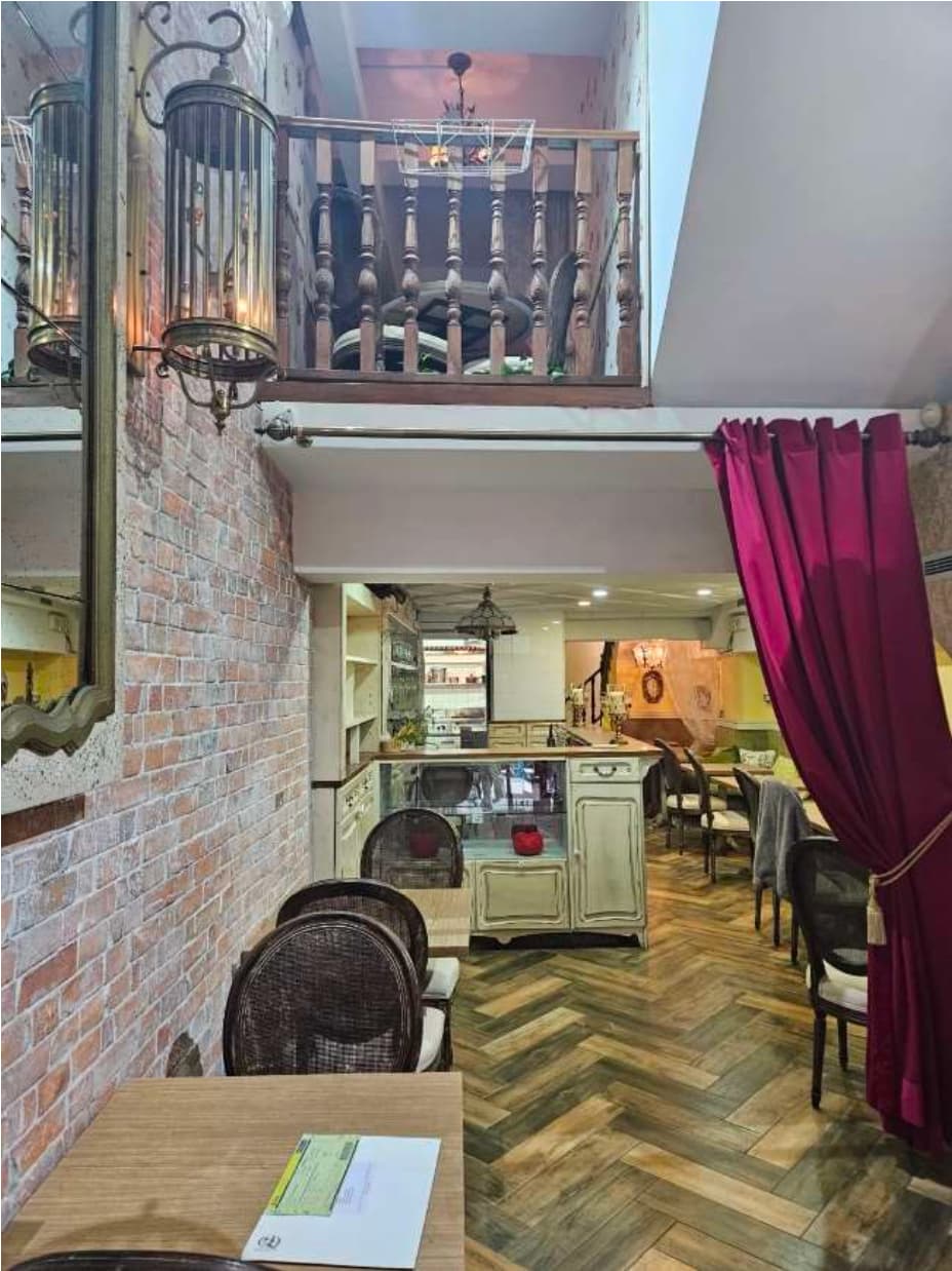 Ref#3632 features a cozy cafe9 interior with rustic brick walls, wooden furniture, herringbone floors, balcony seating, red curtain accents, and decorative lightingan inviting space ideal for renting as a restaurant or shop.