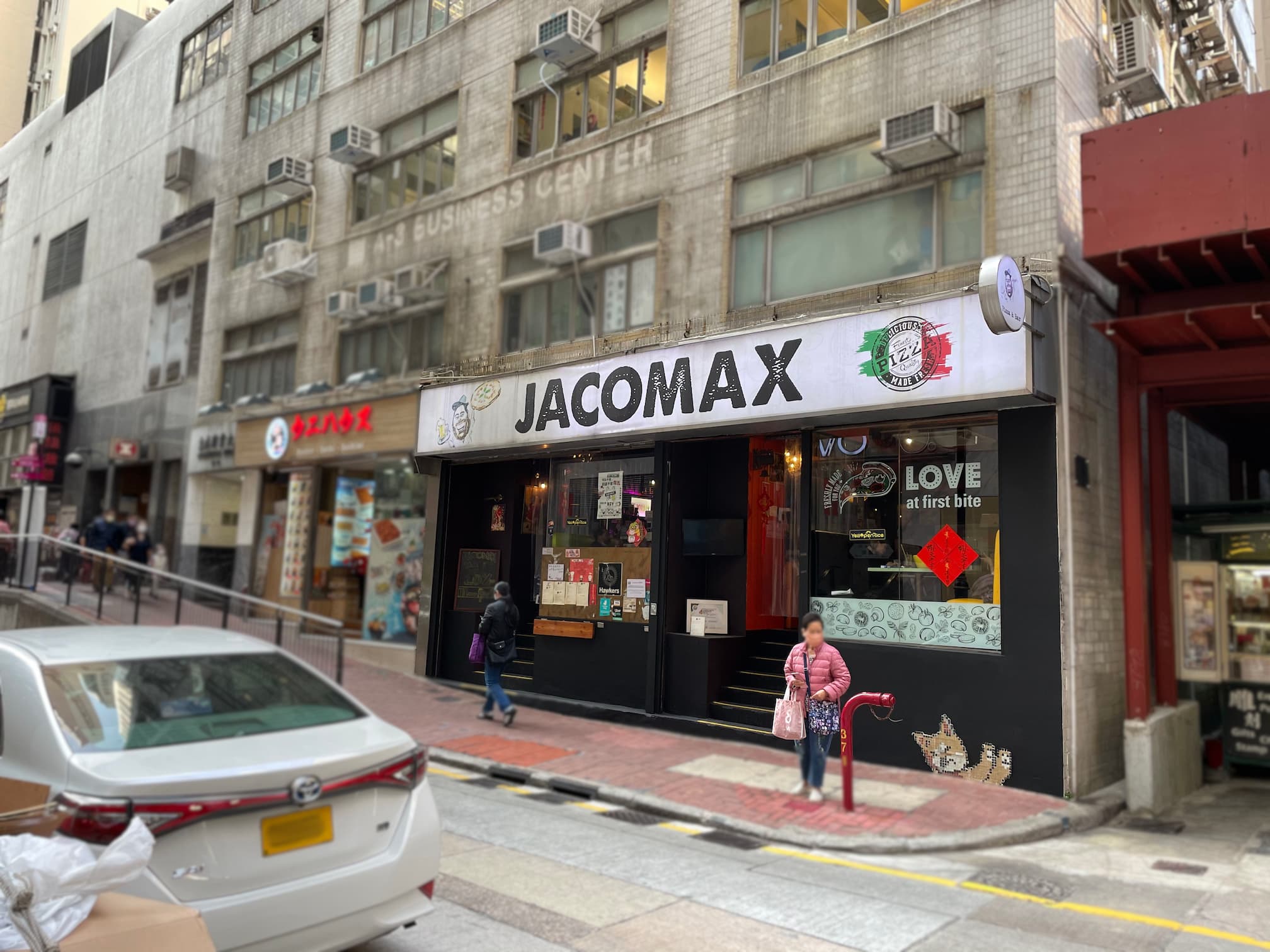 A street view of Ref#3630 restaurant shows a white sign, people passing by, and cars parked outside a multi-story building with nearby rental shops and office spaces available.