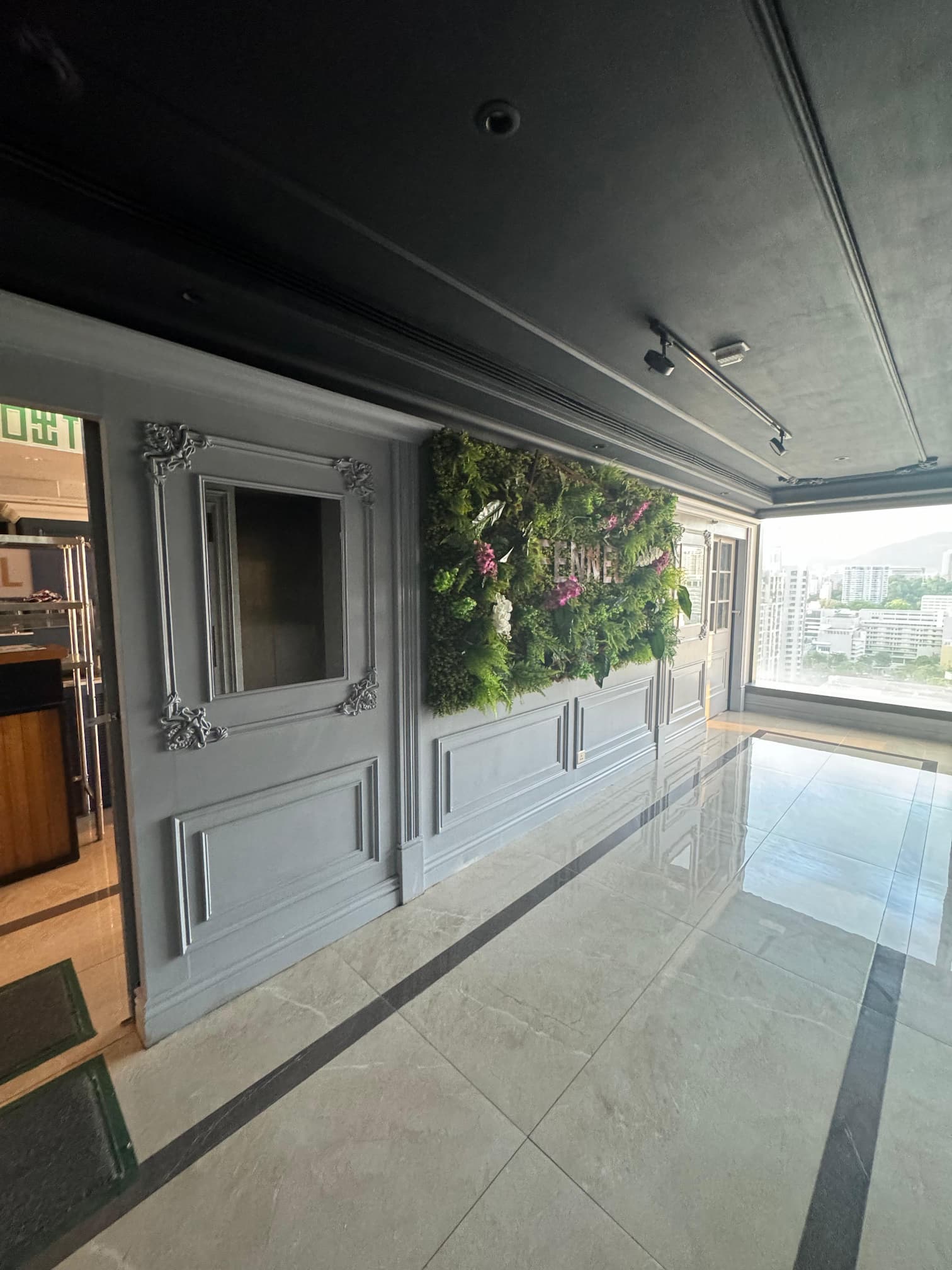 Ref#3612 features shiny tiled floors, gray paneled walls, a framed empty window, and a plant-decorated wallperfect for office rentals. Large windows at the end showcase an impressive cityscape view.