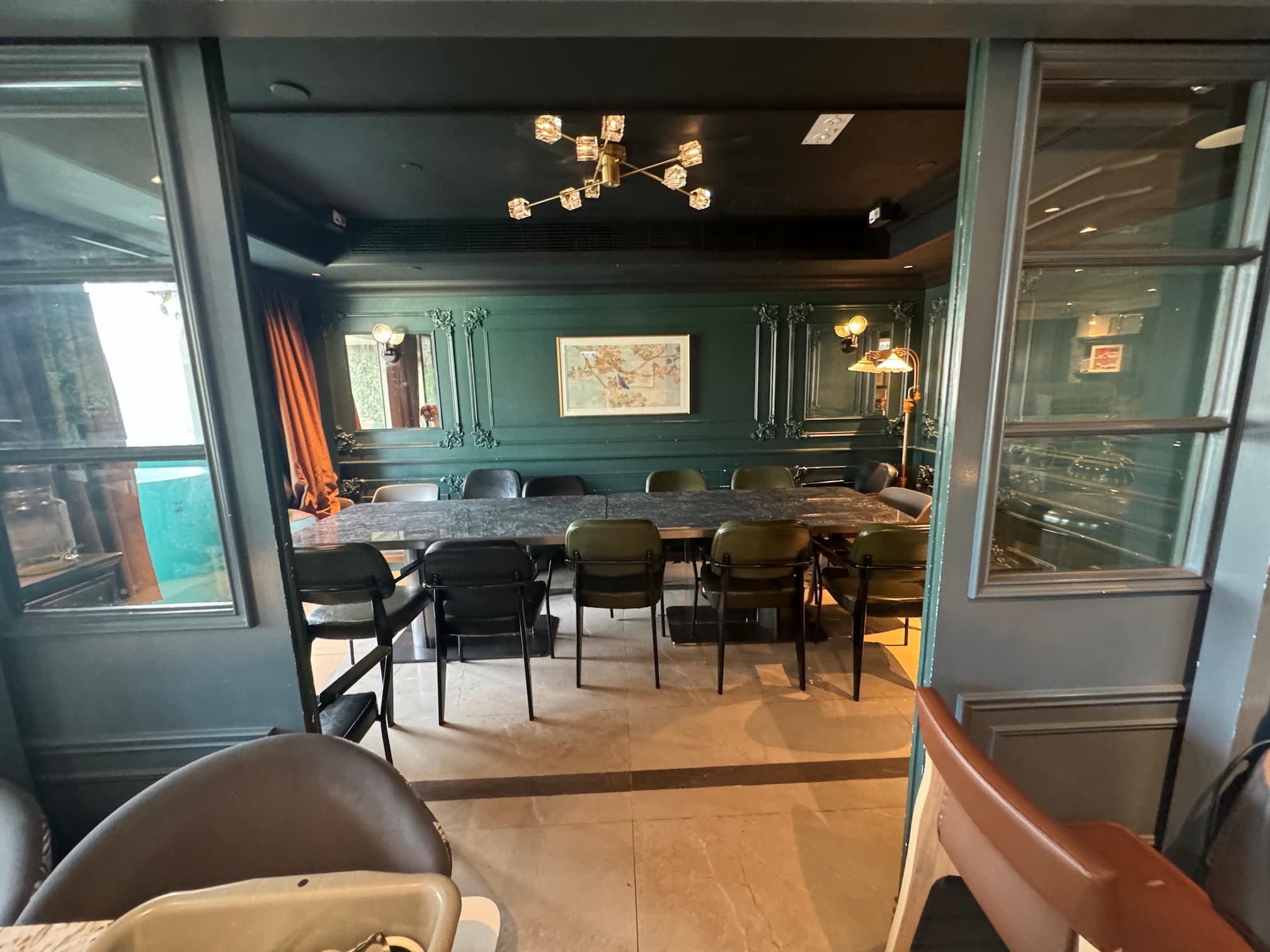 Ref#3612 features a modern conference room with a long rectangular table, chairs, green paneled walls, world map décor, large windows, and a contemporary ceiling lightideal for stylish office space rental.