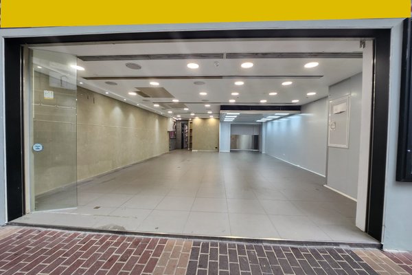 Ref#3404 is an empty, well-lit commercial space with tiled floors, large glass doors, beige walls, and ceiling lights—ideal for use as an office or shop and easily visible from the street through its open entrance.