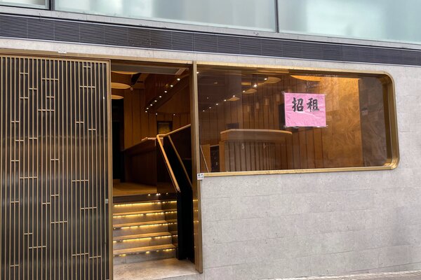 Storefront on Hollywood Road featuring a glass window, interior staircase, and a pink sign displaying Chinese characters.