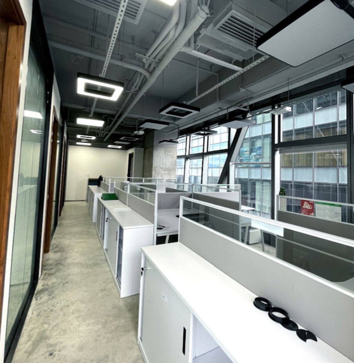 Ref#3281: Modern open-plan office featuring white desks, partitions, large windows for natural light, and exposed ceilings. Ideal for those seeking to rent a clean, unoccupied workspace.