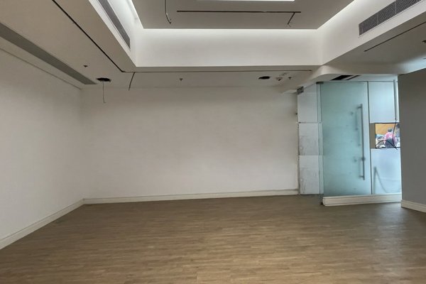 Ref#3355: A clean, modern empty room with light wood floors, white walls, recessed ceiling lights, and a glass door on the right—perfect to rent as a shop or office. No furniture or decorations.