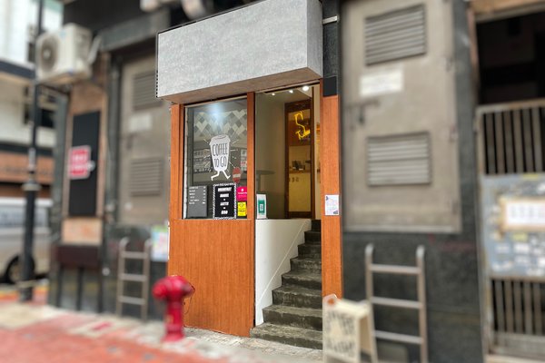 Ref#3129: A small coffee shop entrance with a wooden door frame, menu on the window, stairs inside, and a dark urban exterior. Great shop space to rent; features a red fire hydrant on the sidewalk out front.