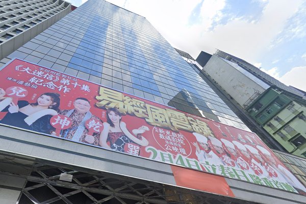 Ref#3574: A tall glass building with a red and yellow Chinese banner stands out, ideal for renting office or shop space. Partly cloudy sky in the background.