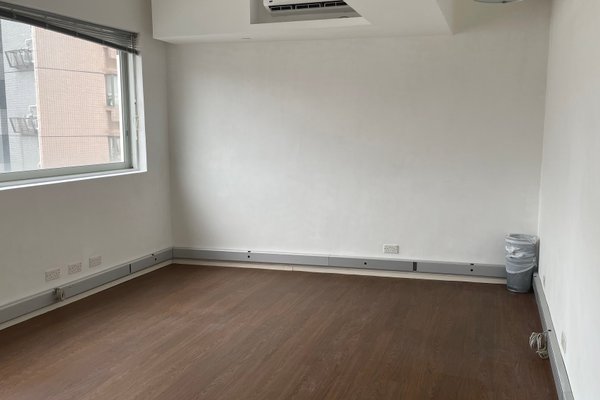 Ref#3440: Bright empty room with white walls, wood flooring, large left window for natural light, outlets along the base, and a corner trash bin
perfect for use as an office or retail rental space.