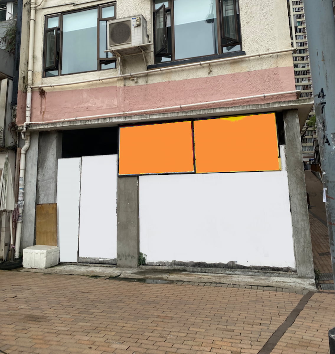 Ref#3565: Closed storefront with boarded-up windows and doors, white and orange panels, air conditioning unit above, situated on a brick-paved sidewalk5perfect for shop or office rental.