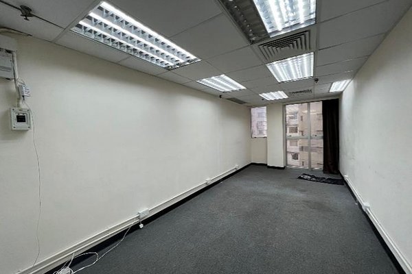 Ref#3406: A narrow office with white walls, gray carpet, fluorescent lighting, exposed wall cables, and a window for natural lightideal office space rental for your business.