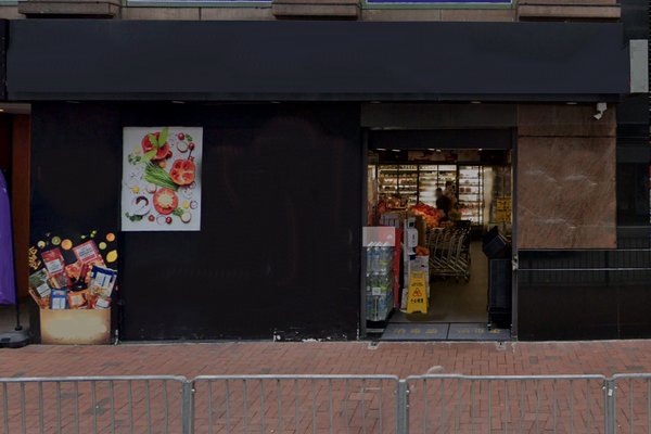 Ref#3263: Grocery store entrance with dark facade, outdoor snacks and drinks, and food poster
ideal for shop rental. Shopping carts and shelves are visible inside through the open doorway.