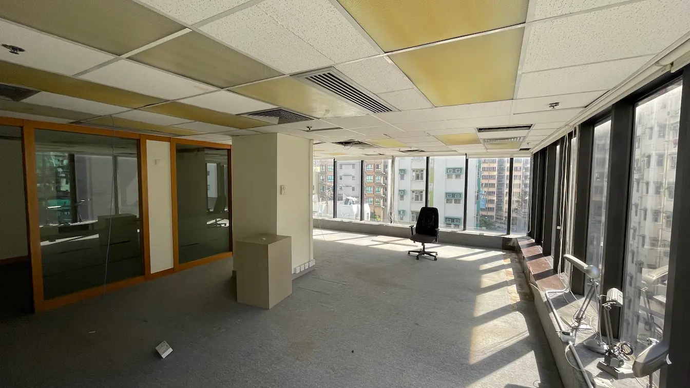 Ref#3302: Spacious office with large windows, city views, scattered ceiling tiles, an office chair, and small cabinets. Sunlit and open—perfect for renting as your next business space.