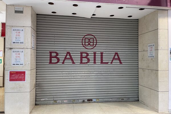A closed metal roller shutter labeled Ref#3566 with a logo. Notices and shop rental signs in Chinese are posted on the nearby beige-tiled walls.