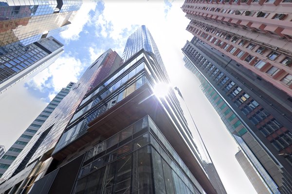Ref#3222: Modern glass-façade skyscraper basking in sunlight under a bright, partly cloudy sky—an ideal low-angle view for renting premium office or shop space among high-rise buildings.