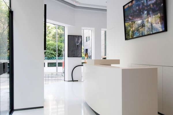 Ref#3217 offers a modern, minimalist reception area with white walls and floors, a curved desk, large windows with tree views, natural light, and a wall-mounted TV—perfect for rent office or shop use.