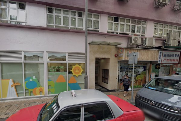 Street view of Ref#3391, a building with colorful shapes and a sun on the windowideal to rent as a shop or office. A red taxi is parked in front, a woman walks by, and a gray van is partially visible on the right.