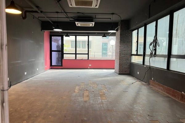 Ref#3541: Vacant room with dark walls, ceiling, large side windows, pink accent wall, and some missing flooring1 perfect for office or shop rental after renovation. Exposed wiring by windows highlights ongoing updates.