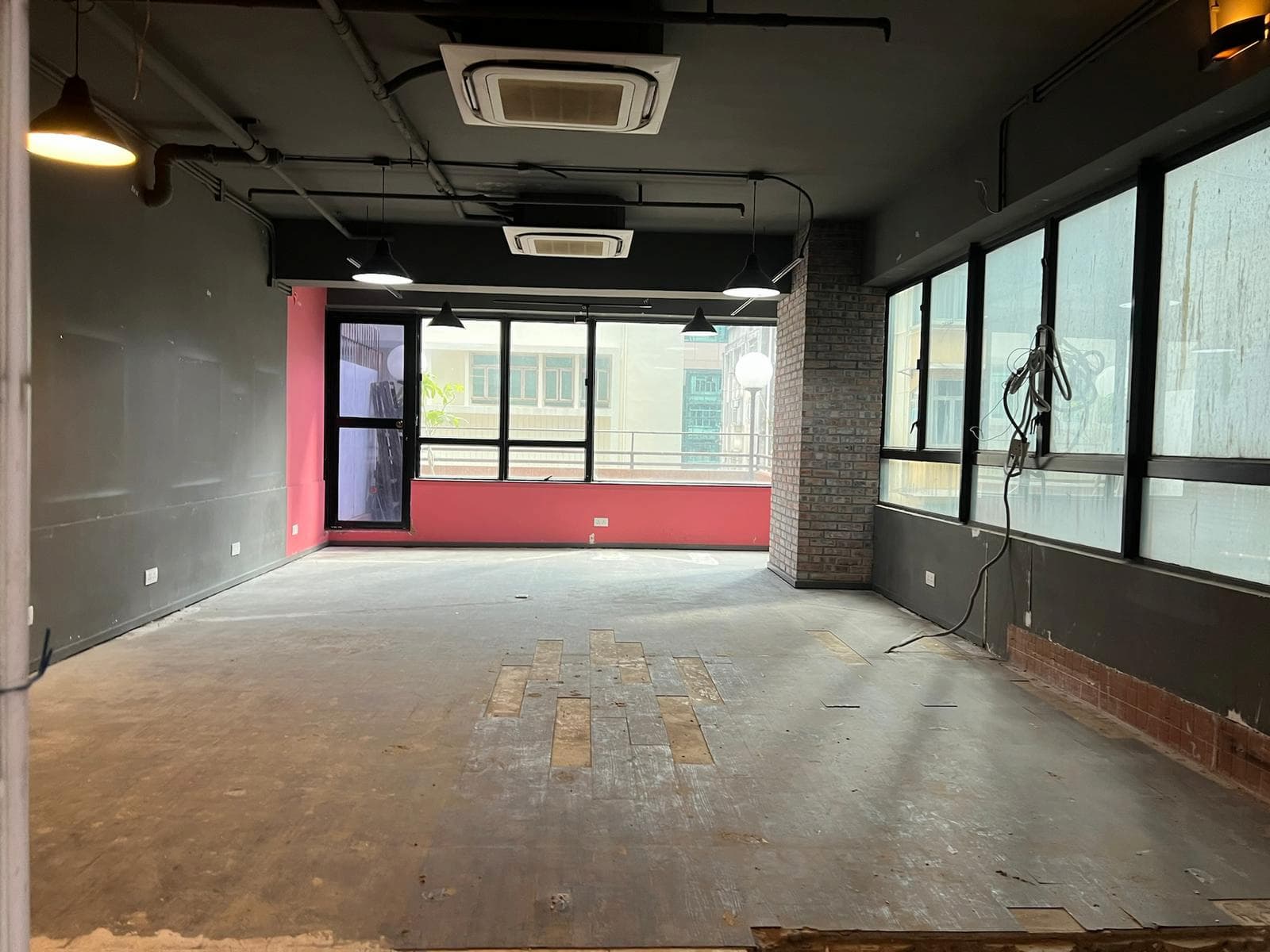 銅鑼灣渣甸街空置房間設大窗戶、外露磚牆、缺失地板及頭頂天花燈。