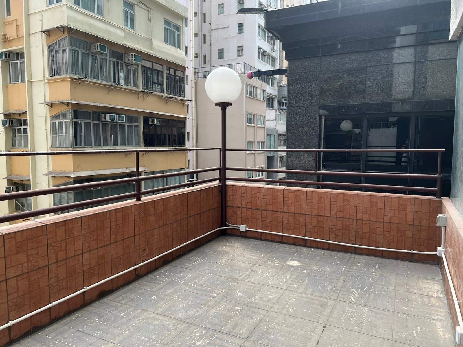 陽台鋪紅色瓷磚及扶手,設圓形燈柱,可俯瞰銅鑼灣渣甸街住宅樓宇。