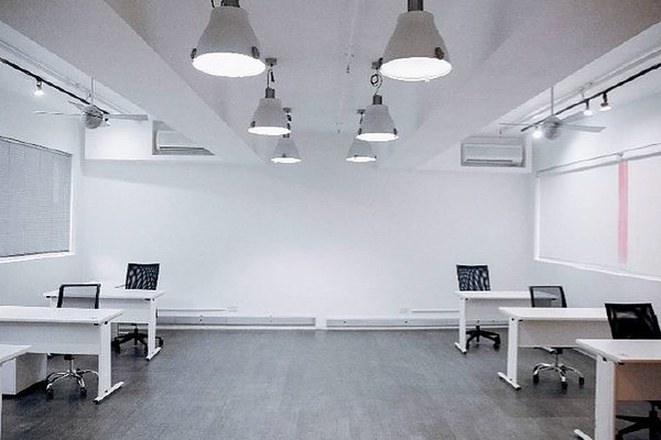 Ref#3151: Modern, minimalistic office space for rent with 4 white desks, black chairs, white walls, large windows with blinds, ceiling lights, and dark wood flooring—perfect for those seeking a stylish workspace.
