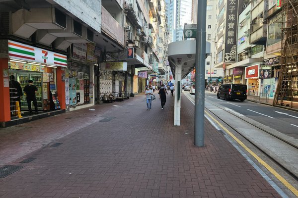 Ref#3577 shows a city street with people on a brick-paved sidewalk by shops, including a 7-Eleven. Cars are parked along the road, and tall buildings offering office or restaurant rentals line both sides.