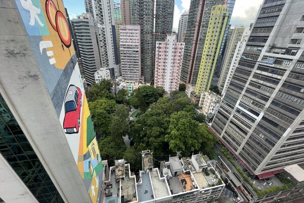 Aerial view of tall colorful apartments, a large red car mural, and a central green park with dense trees
Ref#3285 offers office or shop space for rent in surrounding high-rises.