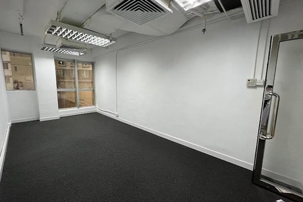Ref#3407 features an empty office with white walls, a large window for natural light, black carpet, ceiling lights, air vents, and a glass door with metal handleperfect to rent as office or shop space.