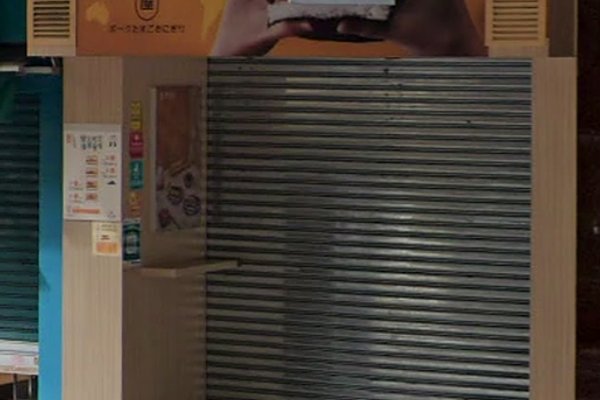 Ref#3244: A closed food stall with a metal shutter, light wood paneling, and a sign featuring hands holding a sandwich. Small posters and menus are on the leftideal for anyone seeking to rent shop or restaurant space.