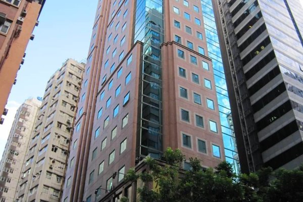 Ref#3382: A tall modern office building with pinkish-brown stone and blue glass, perfect for renting office or shop space, rises among other glass structures and trees under a blue sky.