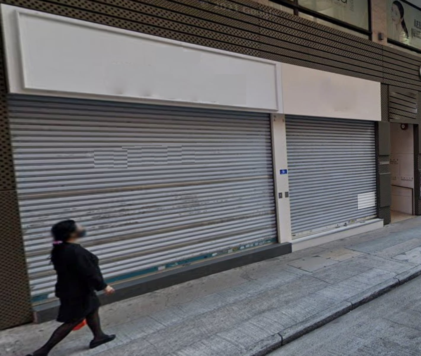 A person walks past two closed metal roller shutter doors beneath blank storefront signs, suggesting Ref#3247 shop rental opportunities are available on the sloped city street pavement.