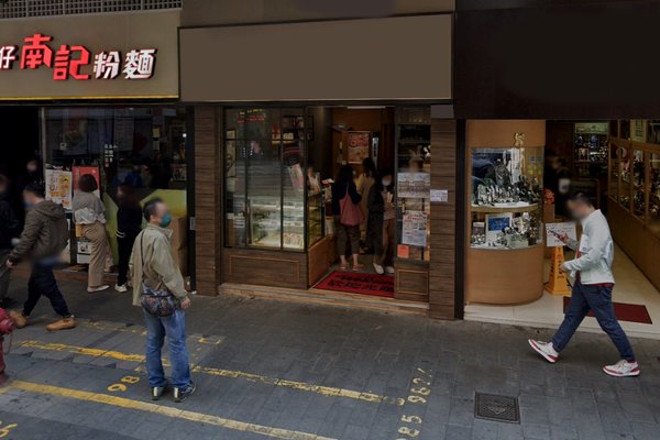 Street view of Ref#3235: a bakery/shop entrance with glass display cases, people nearby, yellow road lines, and neighboring storefronts with Chinese signsideal for those seeking to rent retail or restaurant space.