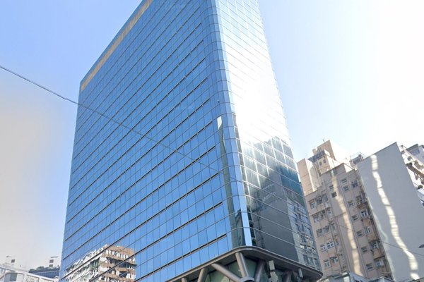 Ref#3153 is a tall, modern glass office building reflecting sunlight, ideal for office rental, and surrounded by other high-rises under a clear blue sky.
