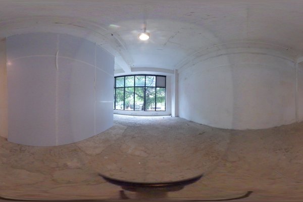 Ref#3293: Spacious, empty room with white walls and concrete floor—perfect for office rental. Large window fills the space with natural light and treetop views; curved partition featured on the left.