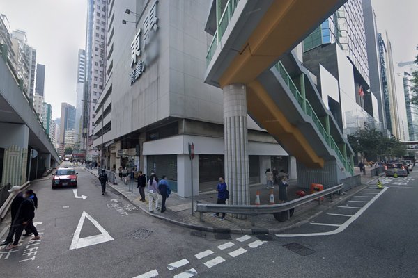 Ref#3276 captures a bustling city street with people on sidewalks, vehicles on the road, blurred shop signage perfect for rental opportunities, a building, and an elevated walkway accessed by stairs.