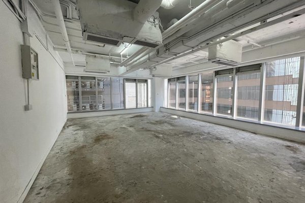 Ref#3511 is an empty, unfurnished industrial space with large windows on two walls, exposed ceiling pipes, and a concrete floor. Well-lit and featuring views of nearby buildings, its ideal to rent as a shop or office.