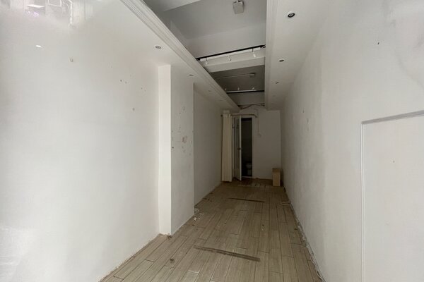 Ref#3453: A compact, unfurnished room with white walls and light wood flooring. Ceiling spotlights illuminate the space, which shows some marks and debris	6ideal for use as an office or shop.