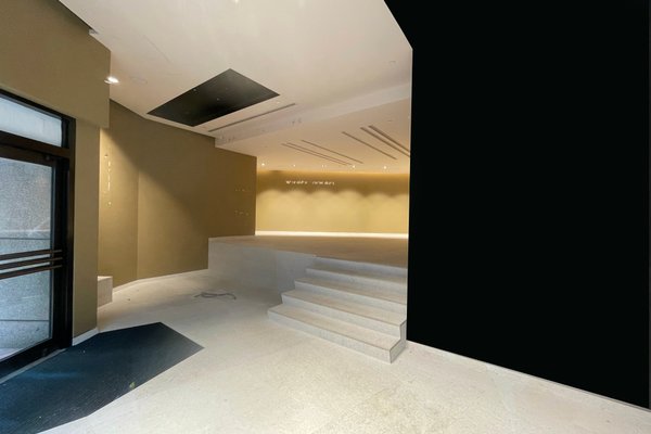Ref#3218: An empty, modern space with beige walls, a raised platform, recessed lights, and a black accent wall	6 ideal to rent as an office or shop. The unfinished look offers flexible options for customization.