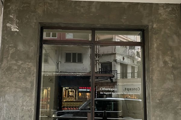 A large window in a gray concrete wall reflects nearby buildings and a black van. The words "Ref#3187" and a tagline on the glass promote unique shop and office rental opportunities across the street.