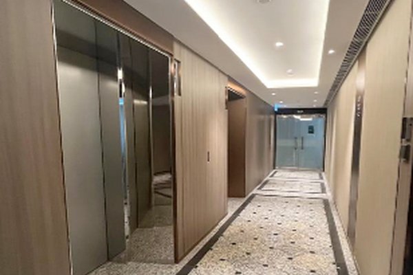 Ref#3154 offers a modern hallway with mirrored elevator doors, light wood walls, patterned tile floors, and glass double doors perfect for renting shop or office space. Ceiling lights brighten the corridor.