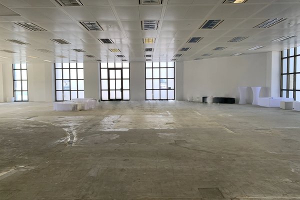 Ref#3300 offers a bright, spacious room with large windows, white walls, and a bare concrete floor. Stacked white tables and chairs are providedperfect to rent as an office or shop with abundant natural light.