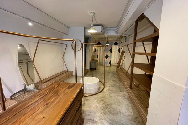 Ref#3450 offers a minimalist space with wooden shelves, dresser, mirrors, geometric wall accents, concrete floors, and exposed pipes perfect for a modern shop rental or creative office.
