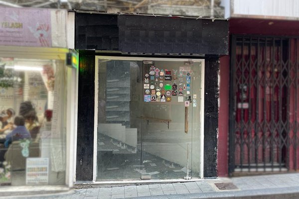 Ref#3352 features a glass door with stickers, opening to an empty, dimly lit storefront with black paneling—perfect for renting as a shop or office. Neighboring shops are closed, and the sidewalk in front is vacant.
