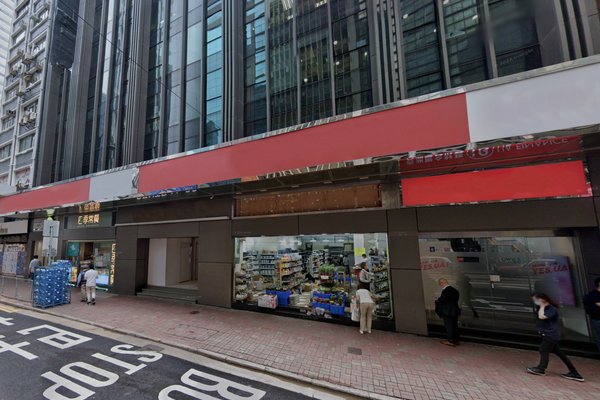 Street view of Ref#3307, a modern building with large glass windows perfect for shop rental, featuring a goods-filled storefront. People walk by on the sidewalk, and road markings appear in the foreground.
