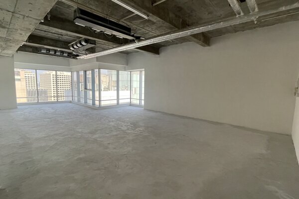 Ref#3361 offers a spacious, empty room with concrete floors, exposed ceiling pipes, and large windows for natural lightideal office space rental with city views.
