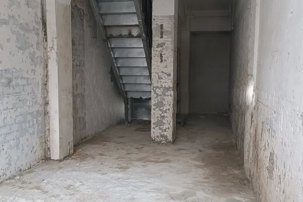 Ref#3128: Unfinished empty concrete space with worn walls, metal staircase, and central square column—perfect to rent as a restaurant, shop, or office for those seeking a unique industrial style.