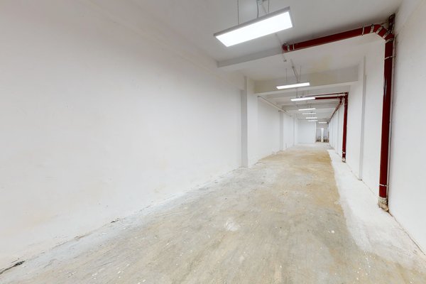 中環榮華里餐廳舖位。狹長空置走廊鋪設混凝土地面,天花外露紅色喉管,並設有光管照明。