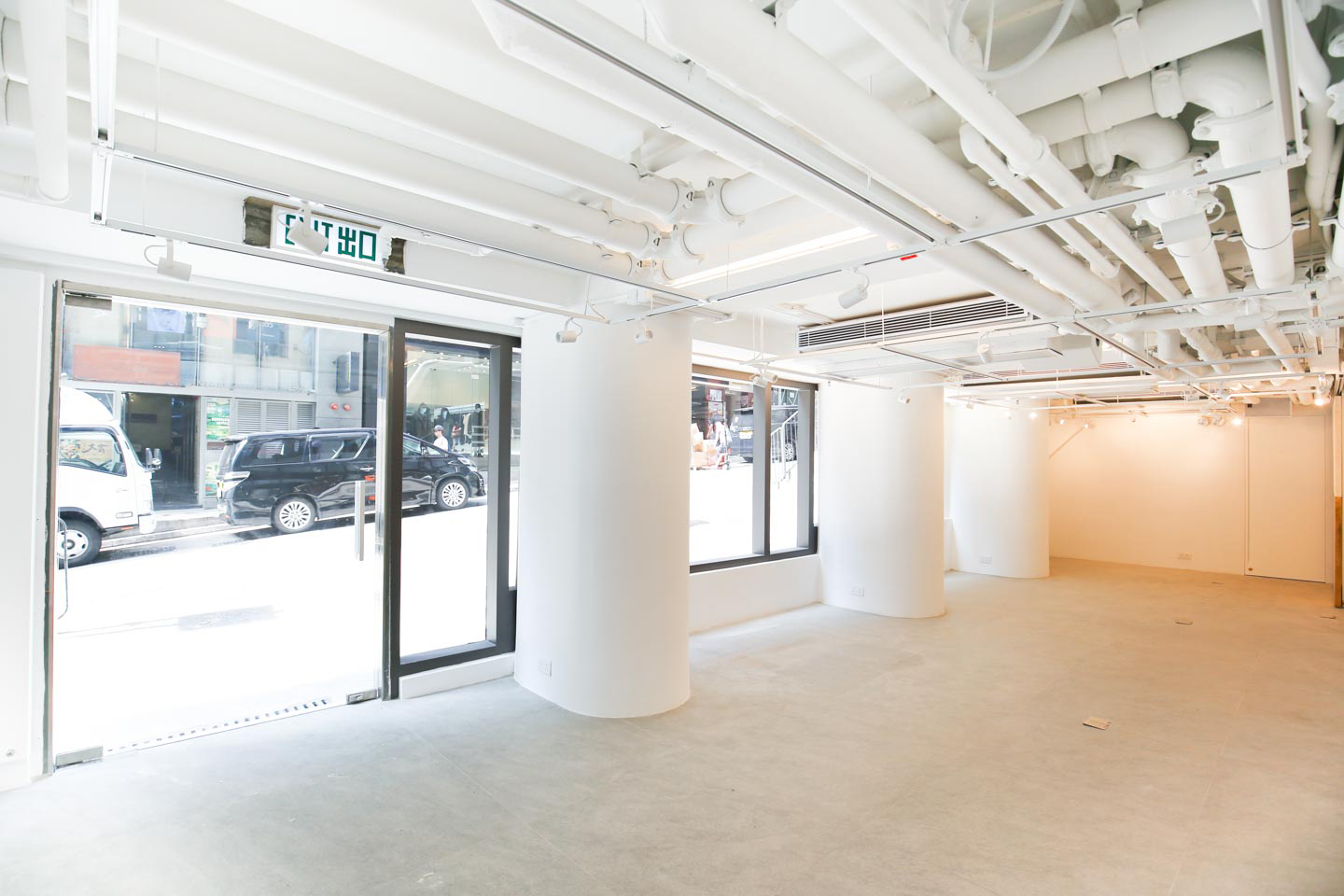 Ref#3489 is a bright, empty commercial space with large windows, white walls, and exposed ceiling pipes—ideal to lease for a restaurant or rent as a shop. Sunlight fills the clean, open interior from the street.