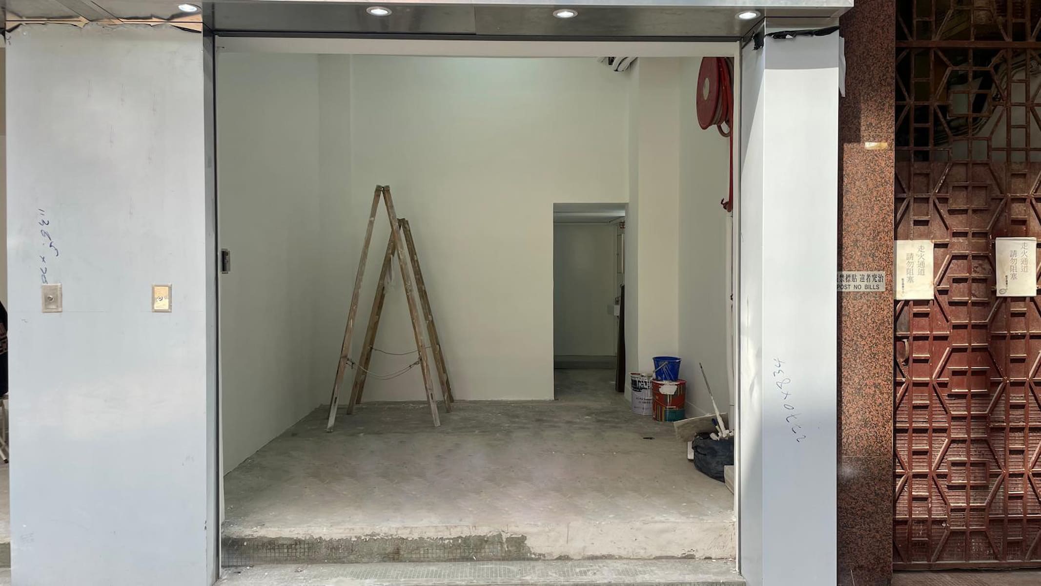 Ref#3039: A small, empty shop with white walls, unfinished concrete floor, and a wooden ladder inside. Paint cans and supplies suggest ongoing renovations
perfect for those seeking rental shop or office space.