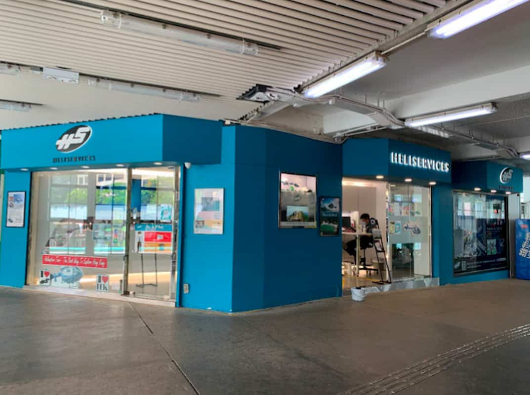 Ref#3010 features a blue “Hellseservices” storefront in a brightly lit building, offering shop rentals with glass windows, display posters, concrete floors, and white panel ceilings with lights. A few people are seen near the entrance.